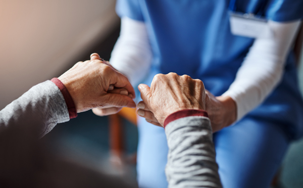 Closeup of nurse holding patients hands