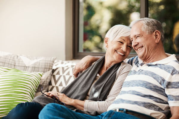 Elderly couple on couch smiling.